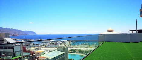 A high-rise building with a rooftop pool and a view of the sea.