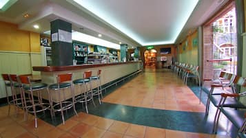 A bar area with multiple stools, a counter with a variety of bottles, and a seating area with chairs.