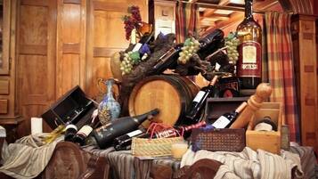 Une pièce encombrée, meublée de meubles en bois, avec une grande barrique à vin et diverses bouteilles de vin.