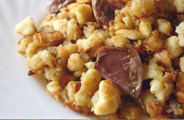 Primer plano de un plato con pan desmenuzado y trozos de fruta.