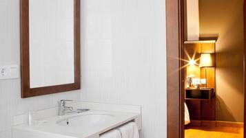 Un baño moderno con un lavamanos blanco, un espejo con marco de madera y una toalla colgada en la pared.