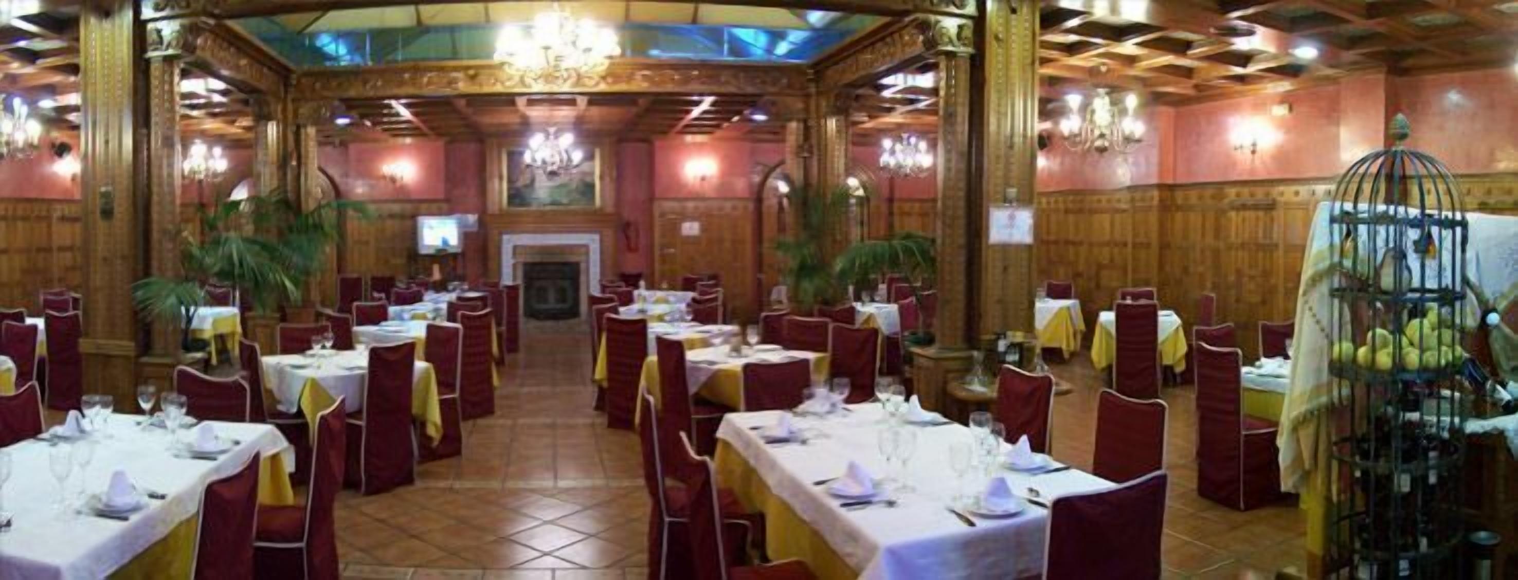 A banquet hall with tables set for dining, a chandelier, and a birdcage.