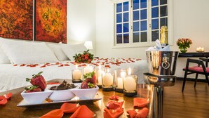 A hotel room with a bed, bedside tables, a window, and a decorative setup with candles and flowers. - Matisse Hotel (Bogotá)