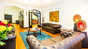 A modern living room with a sectional sofa, a coffee table, and a blue rug. There is a staircase leading to another level, and a painting on the wall. - Matisse Hotel (Bogotá)
