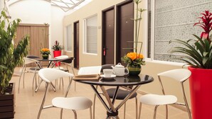 A modern indoor space with a glass ceiling, multiple tables with chairs, and potted plants. - Matisse Hotel (Bogotá)