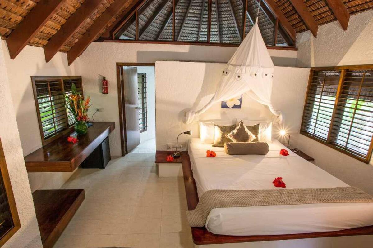Un dormitorio con cama, mesita de noche y ventana con persianas.