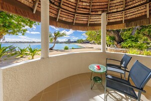 Un área de estar al aire libre techada con vista a la playa y al océano.