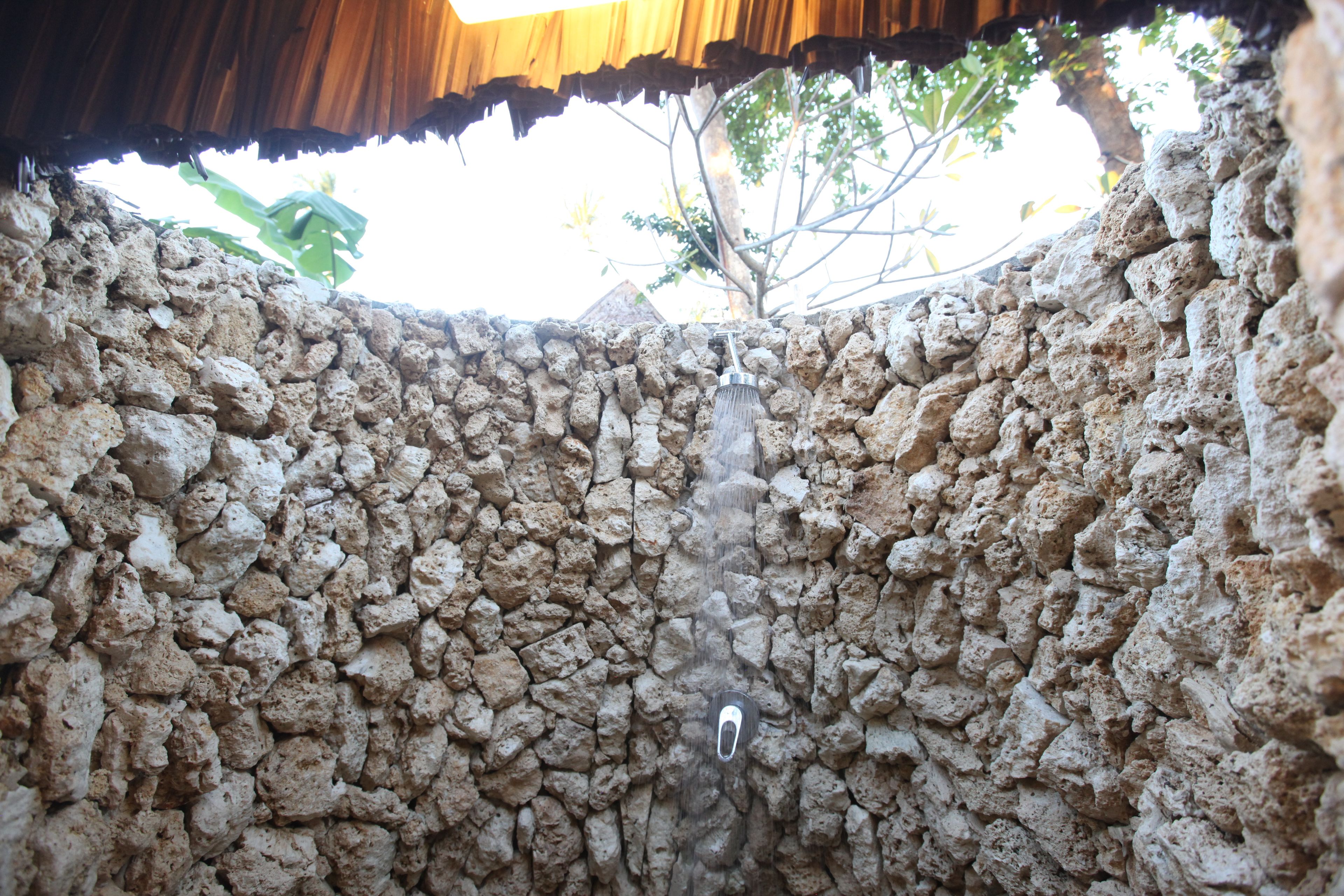 Una pared de piedra con un cabezal de ducha.