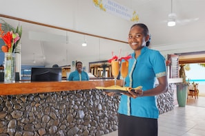A reception area with a stone wall, a reception desk, and a sign for 'Reception & Guest Relations'. - Breakas Beach Resort - Adults only (Port Vila)