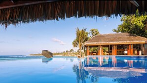 An infinity pool with a view of the ocean, a thatched-roof structure, and palm trees. - The Beach Vanuatu (Port Vila)