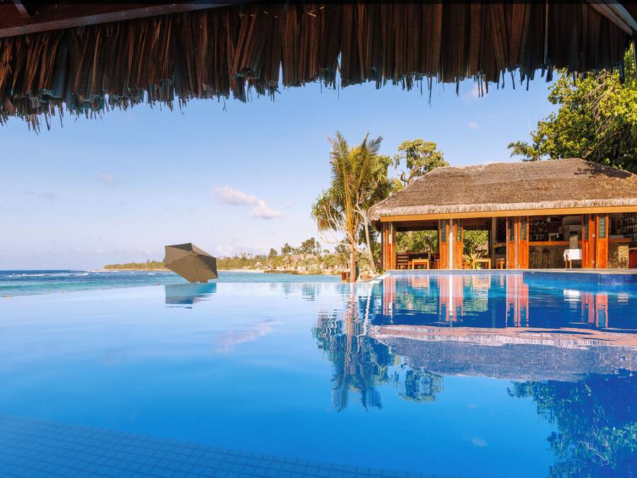 Una piscina al aire libre, sombrillas, sillones reclinables de piscina