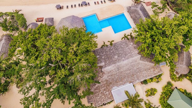 An aerial view of a beach resort with a clear blue pool, lounge chairs, and thatched-roof structures. - The Beach Vanuatu (Port Vila)