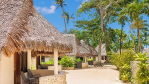 A resort with thatched-roof huts, outdoor seating, and lush greenery. - The Beach (Port Vila)