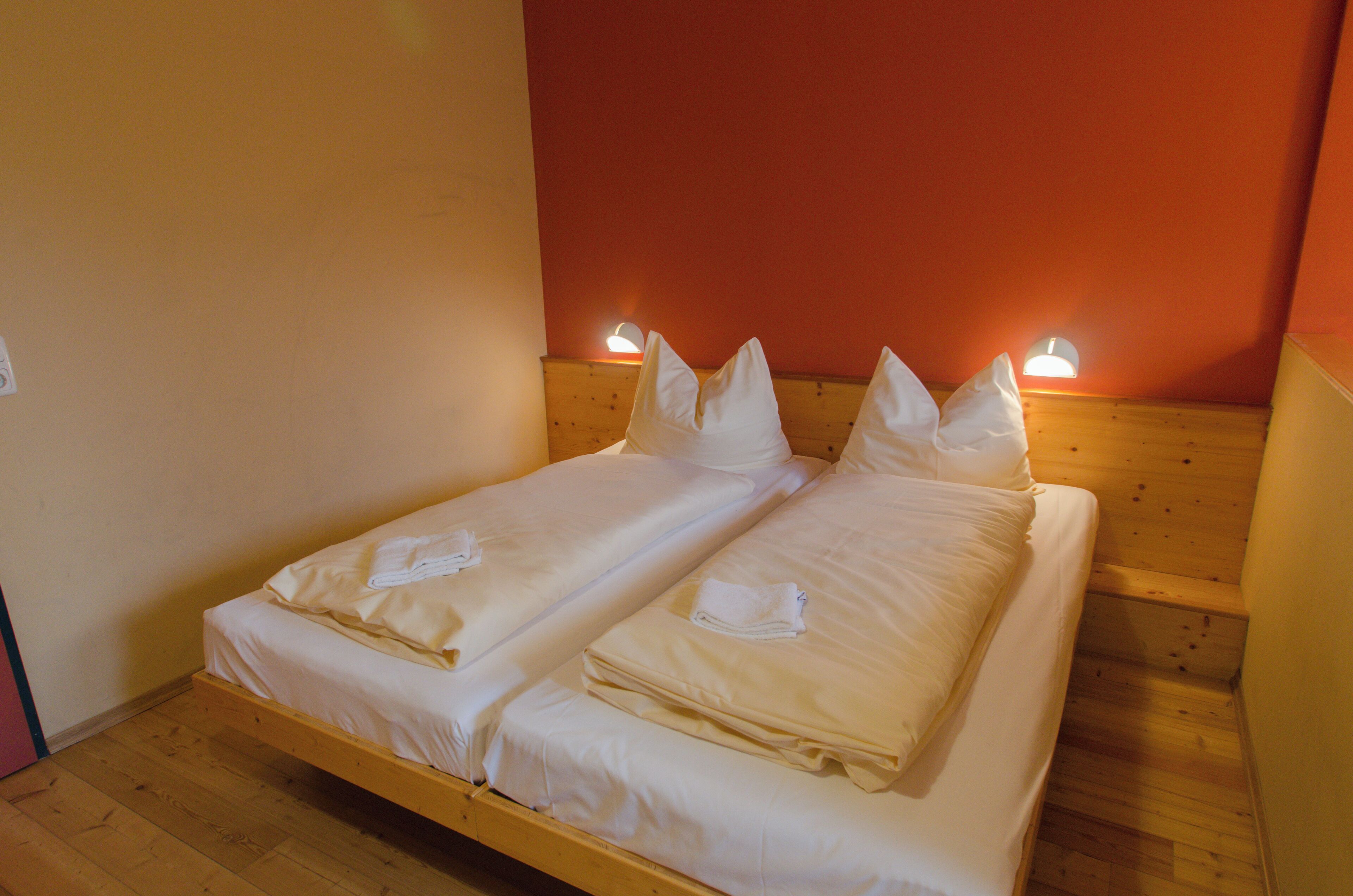 A double bed with white linens and pillows, two bedside lamps, and a wooden headboard.