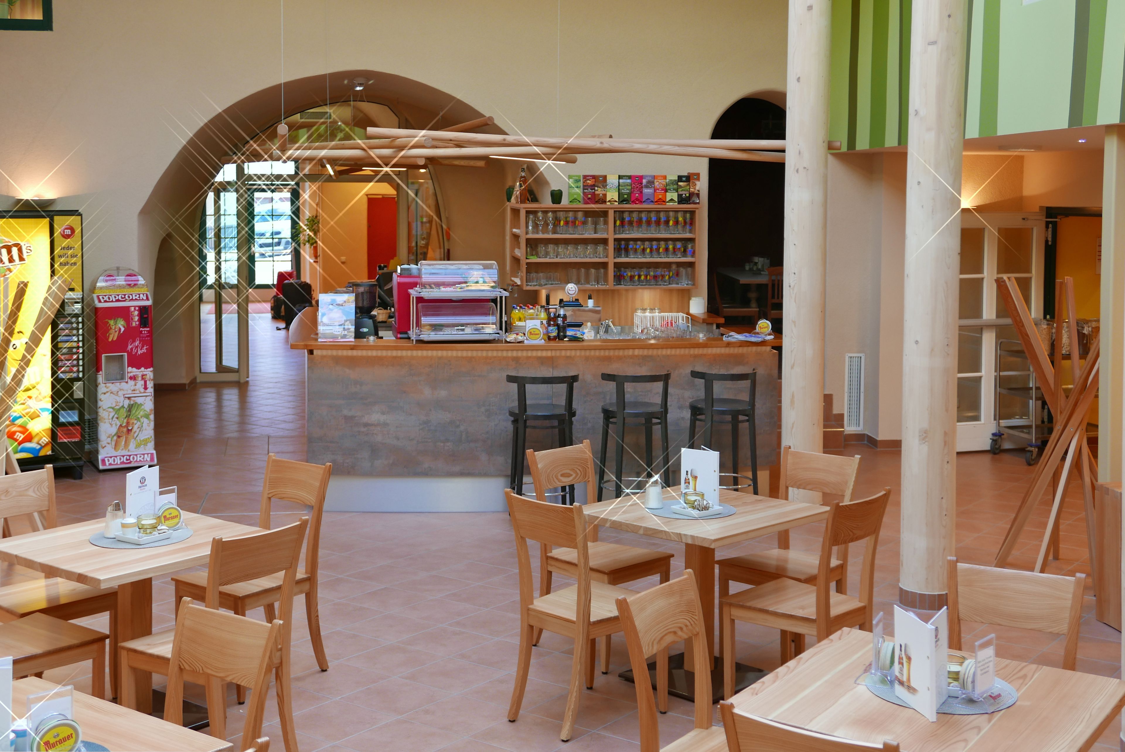 A restaurant with wooden tables and chairs, a counter with a menu, and a popcorn machine.