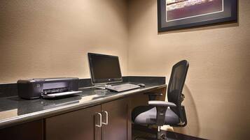 A workspace with a laptop, printer, and chair.