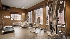 A fitness center with cardio machines, weight training equipment, and large windows.