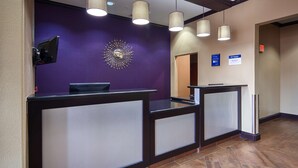 A reception area with a purple wall, a decorative sunburst mirror, and three pendant lights.