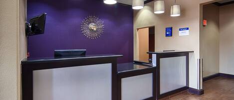 Zona de recepción con pared morada, un espejo decorativo con diseño de sol y tres lámparas colgantes.