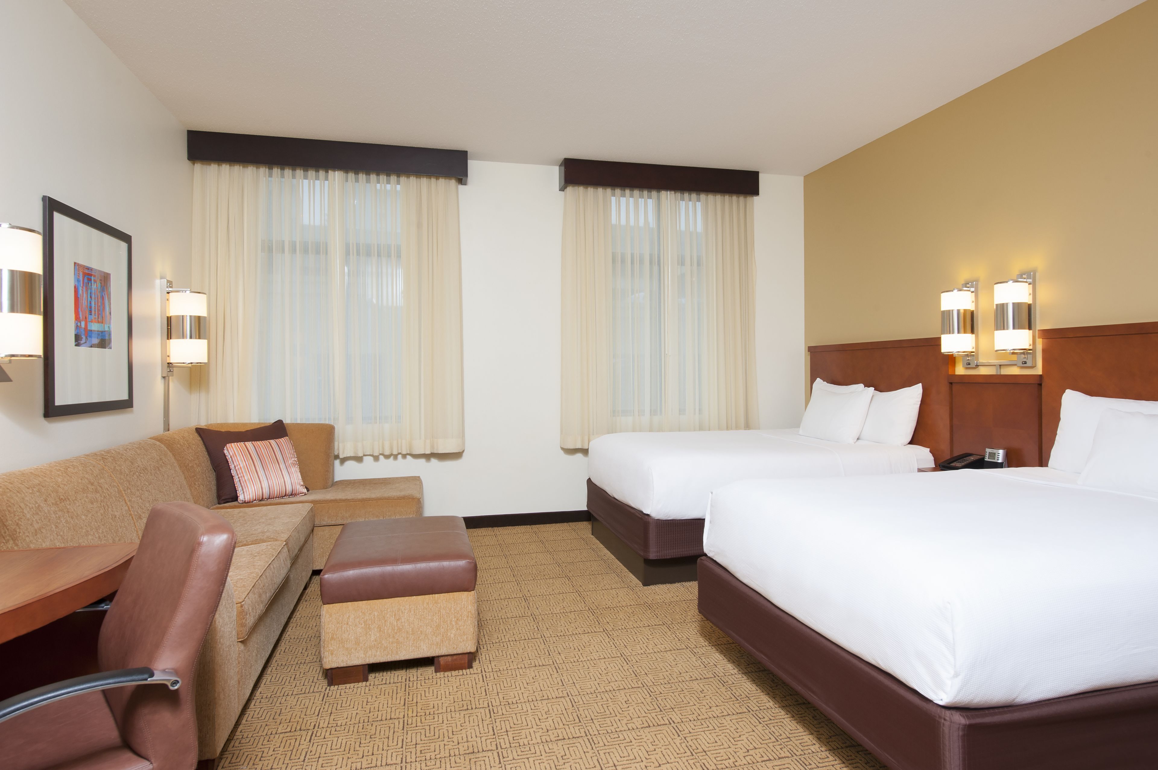 Ein Hotelzimmer mit zwei Betten, einem Schlafsofa, einem kleinen Tisch und einem Sessel.