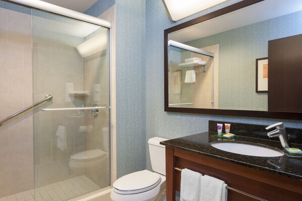 A modern bathroom with a glass-enclosed shower, a white toilet, and a sink with a dark countertop.