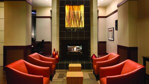 A lobby with a fireplace, red leather chairs, and a decorative wall panel. - Hyatt Place Des Moines/Downtown (Des Moines)