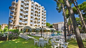 Un hotel con varios balcones, piscina y zonas de estar al aire libre.