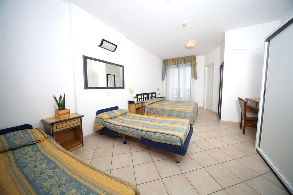 A bedroom with two beds, a desk, and a chair.