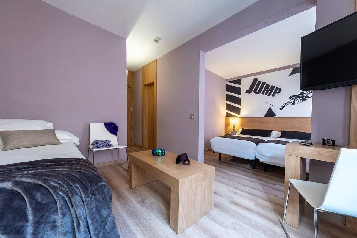 A modern hotel room with a bed, a desk, a chair, and a TV.