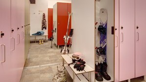 Un vestiaire avec des casiers roses, un banc et du matériel de ski.