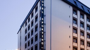 Un bâtiment d’hôtel avec une enseigne indiquant « HÔTEL SPORTING ».