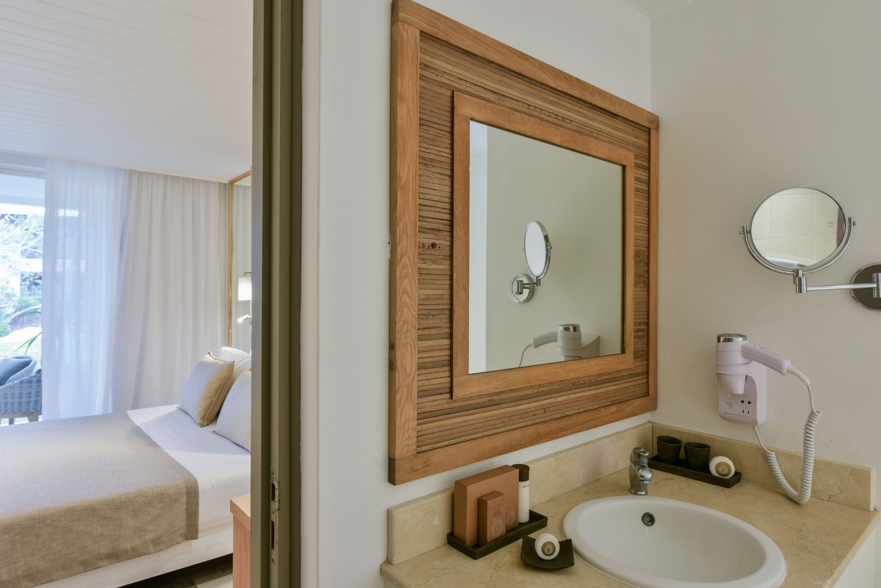 A hotel bathroom with a large mirror, a sink, and a hairdryer.