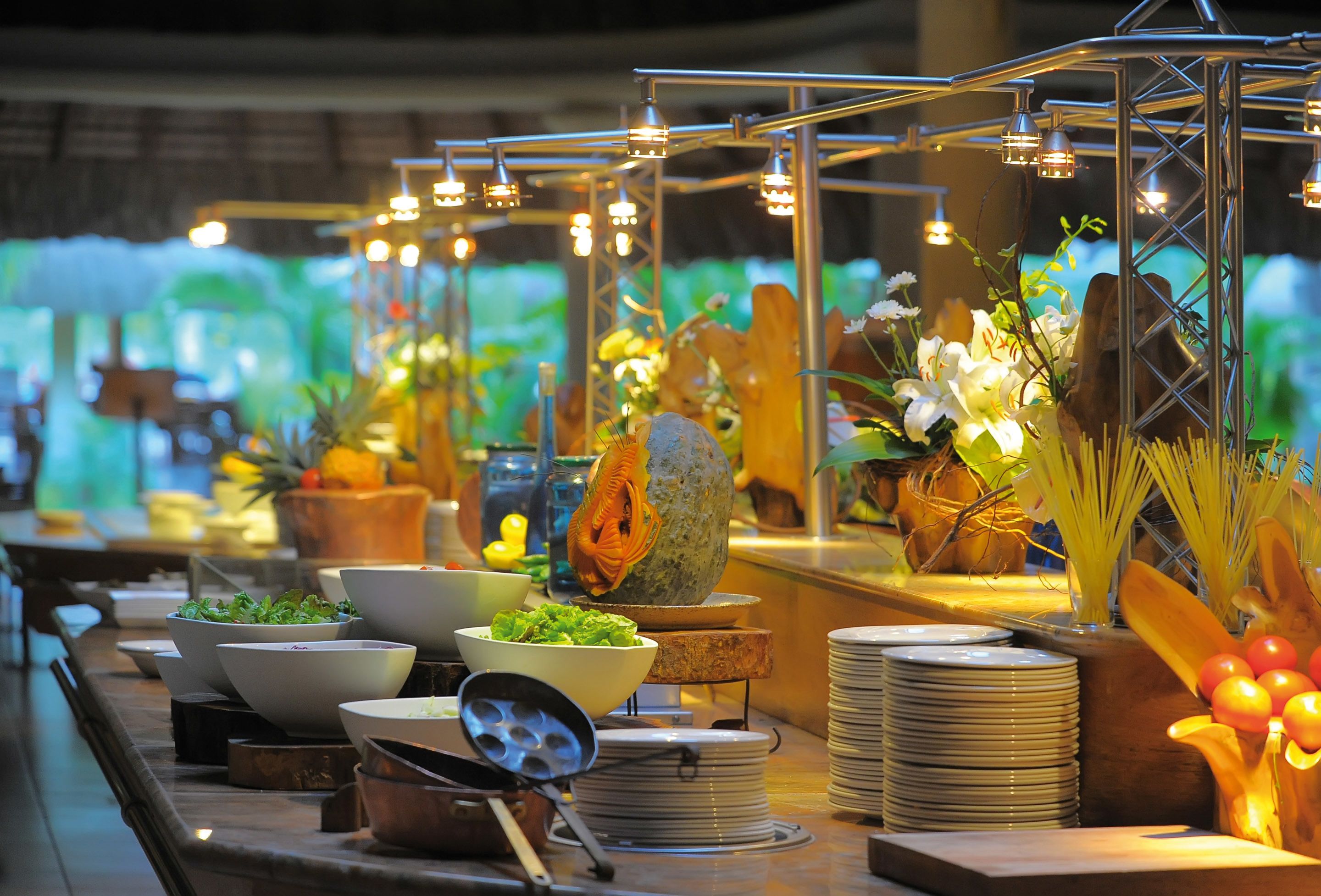 Un buffet proposant une variété de plats et d’ustensiles, notamment des bols, des assiettes et un grand centre de table décoratif.