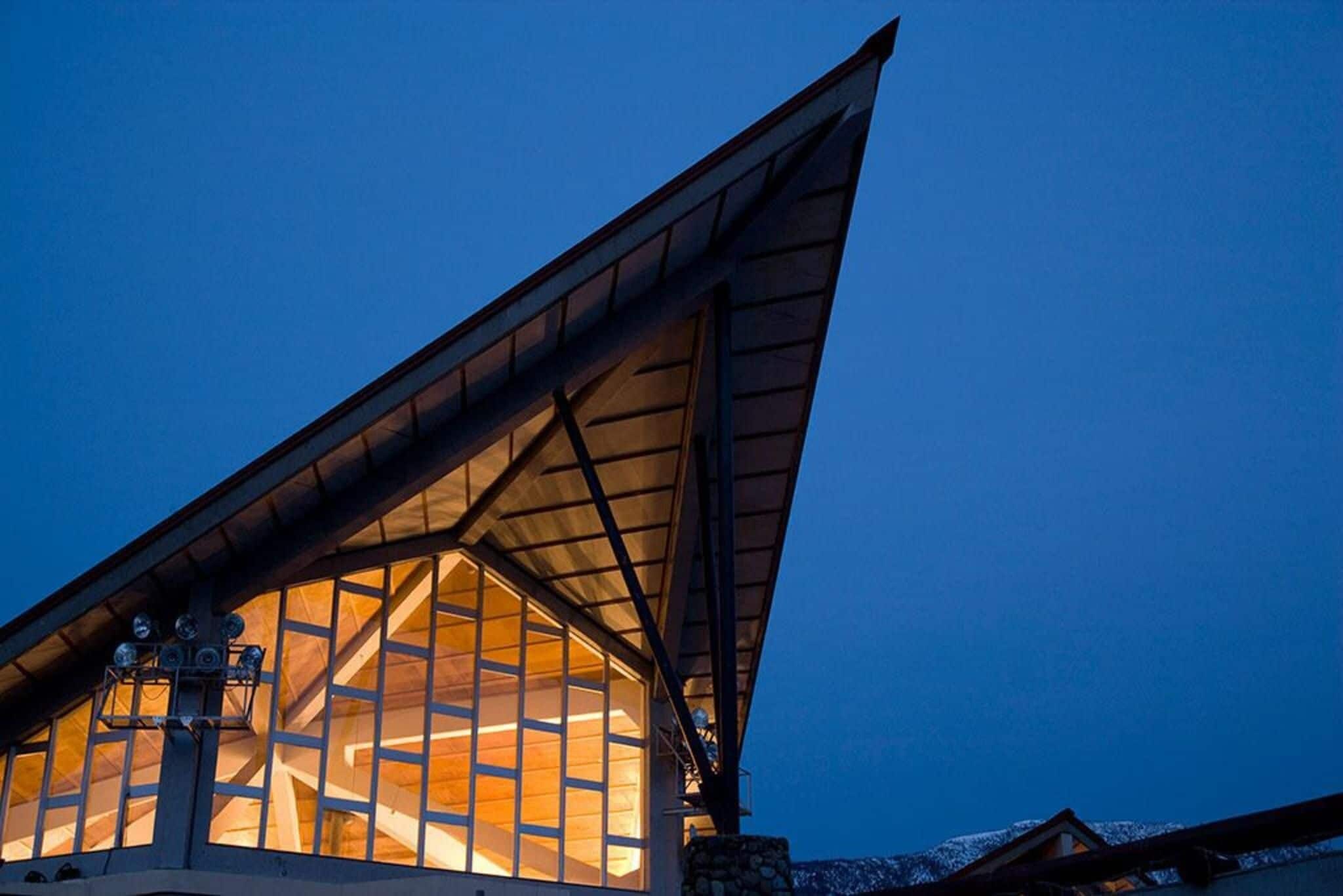 A building with a large, triangular roof structure and a prominent, illuminated interior space.