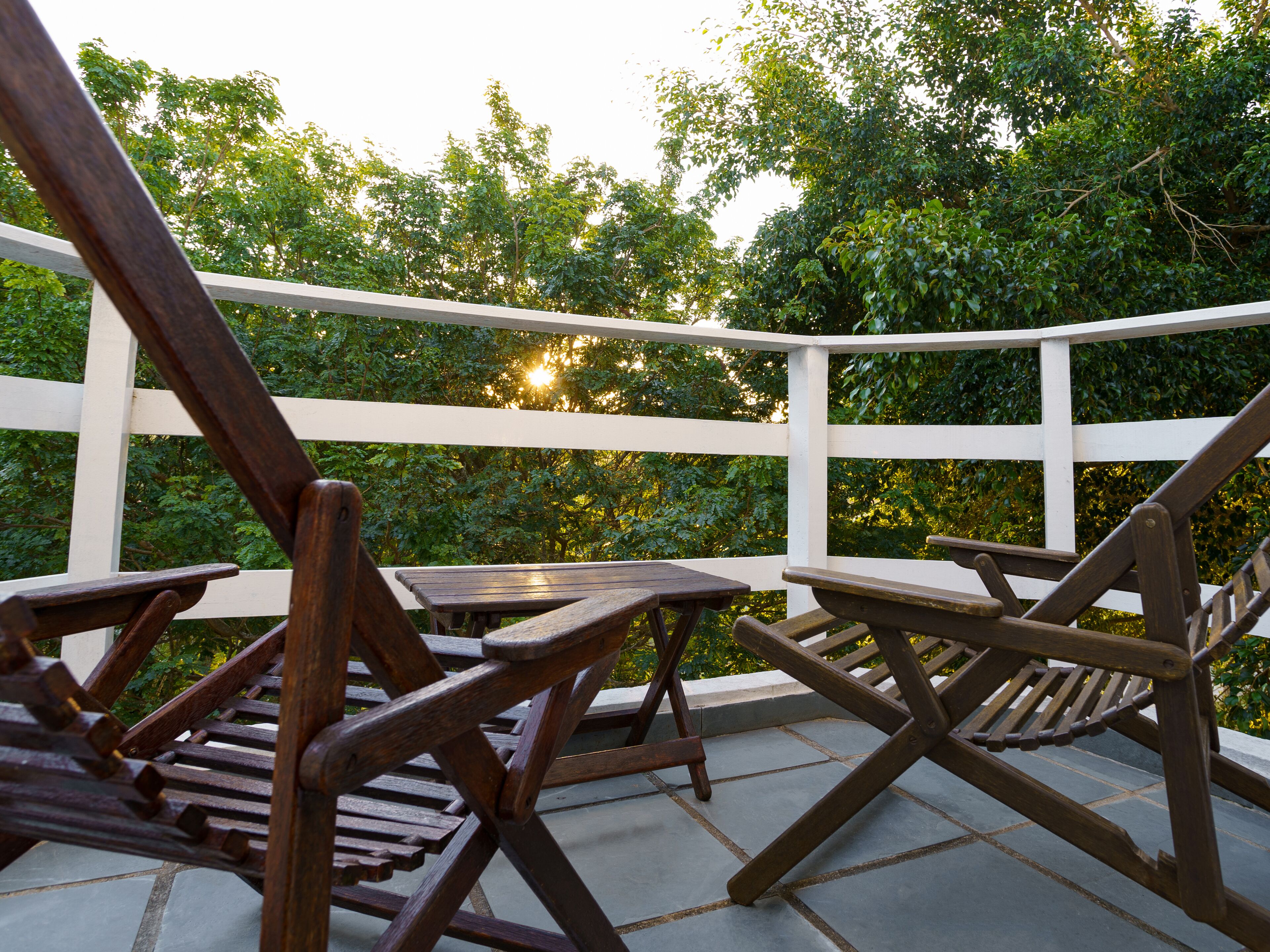 Una terraza de madera con barandilla blanca, con una mesa y sillas.