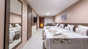 A hotel room with a long corridor, multiple beds, a TV, and a large mirror. - Amuarama Hotel (Fortaleza)