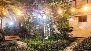 A courtyard with a bench, a pergola with flowers, and a pathway. - Amuarama Hotel (Fortaleza)