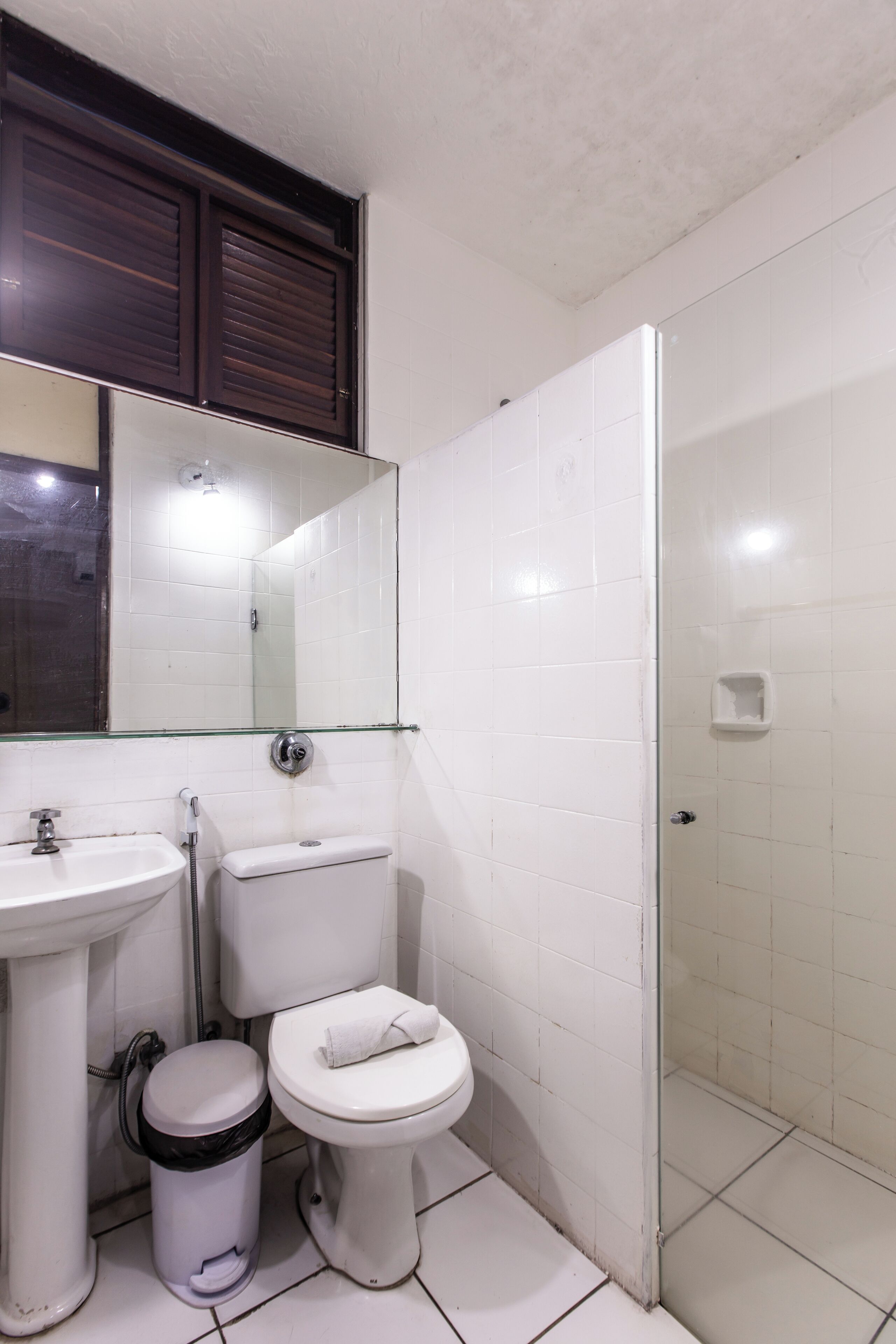 A bathroom with a white sink, toilet, and glass shower enclosure.