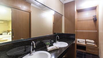 Un baño con dos lavamanos, un espejo grande y un mueble de tocador de madera con un perchero para toallas.
