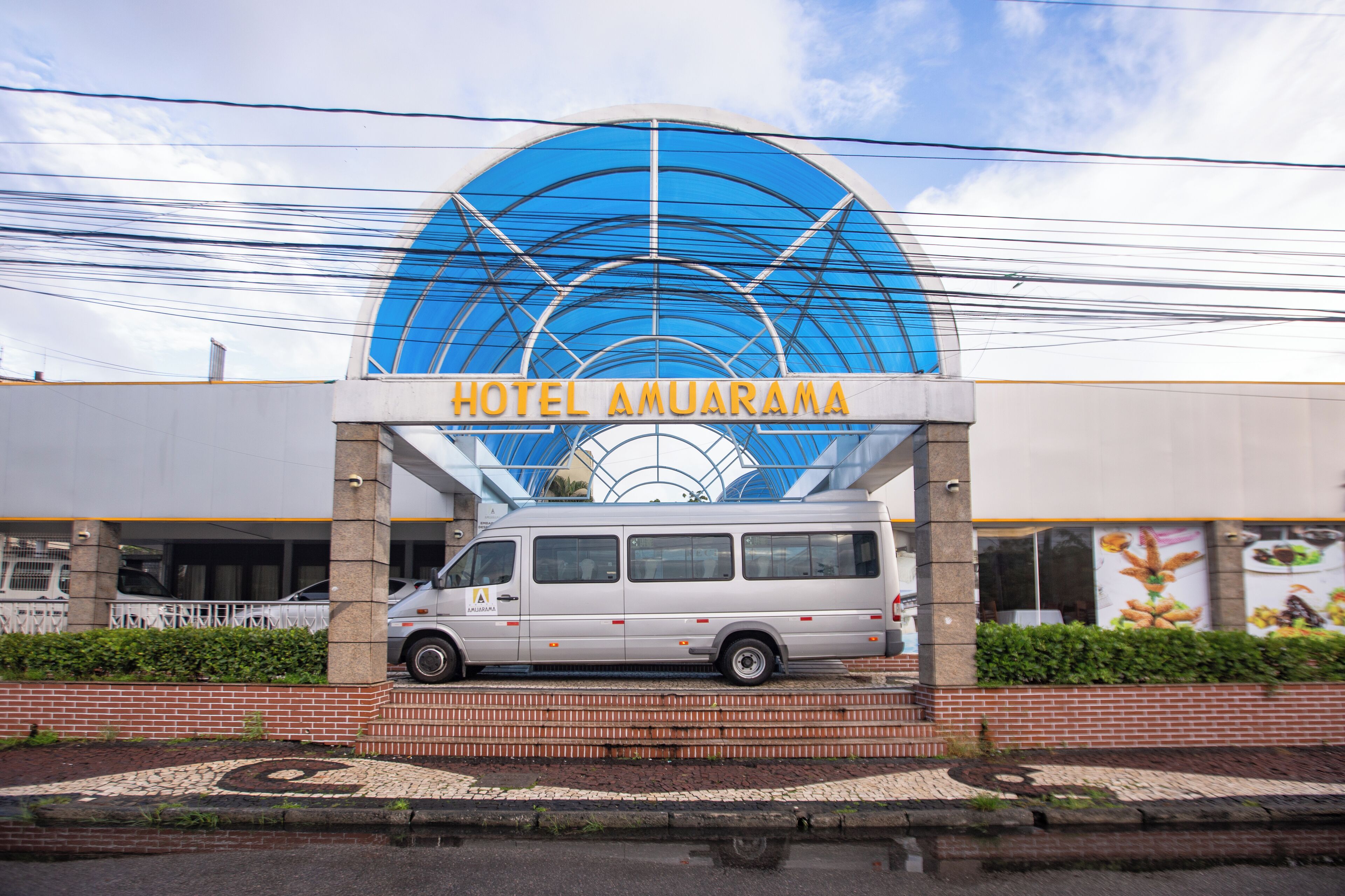 A hotel entrance with a large blue arch and the name "HOTEL AMUARAMA" displayed above.