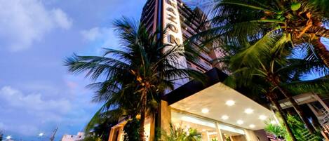 A hotel with a modern design, featuring a prominent vertical structure and a well-lit entrance.
