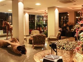 Un vestíbulo con una gran escultura de caballo, muebles de mimbre y una planta en maceta con flores rojas.