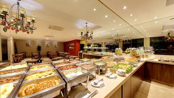 A buffet area with various food options, a seating area with tables and chairs, and a decorative chandelier.