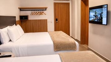 A hotel room with a bed, a TV, a wardrobe, and a wall-mounted air conditioner.