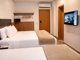 Habitación de hotel con una cama, televisión, armario y aire acondicionado instalado en la pared.