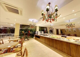 Un restaurante moderno con una isla central, mesas redondas y candelabros colgantes.