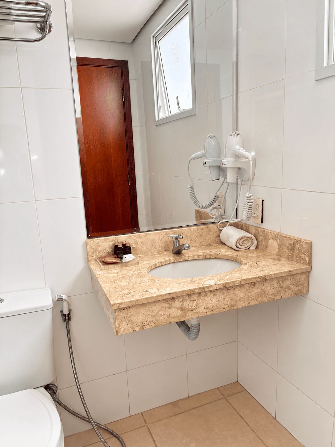 A bathroom with a marble sink, a hairdryer, and a towel.