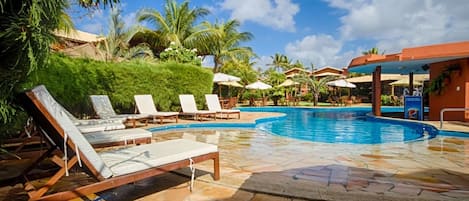 A pool area with lounge chairs, palm trees, and a clear blue sky.