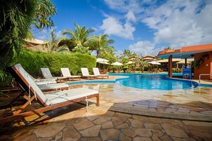 A pool area with lounge chairs, palm trees, and a clear blue sky.