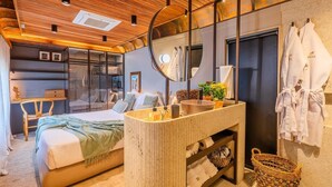 Een moderne slaapkamer met een groot bed, een kaptafel met spiegel en uitzicht op de stad door een glazen wand.
